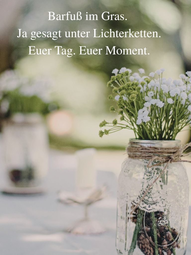Hochzeitsdeko aus echter Keramik – Ringschale mit persönlicher Prägung und Leinenband Vase mit Blumen auf einem Tisch im Freien, umgeben von Lichterketten.