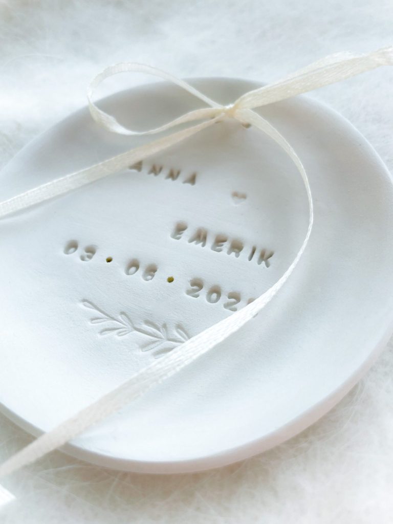Boho Ringschale Hochzeit mit Schleierkraut und Initialen – personalisierbar und handgeformt Vase mit Blumen auf einem Tisch im Freien, umgeben von Lichterketten.
